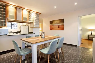 a kitchen and dining room with a wooden table and chairs at Cap Du Mont Cape Town in Bloubergstrand