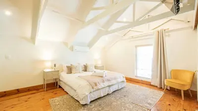 a white bedroom with a bed and a chair at Waymaker Cottage in Franschhoek