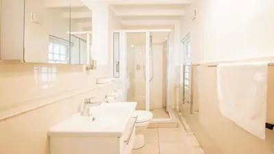 a white bathroom with a toilet and a sink at Waymaker Cottage in Franschhoek