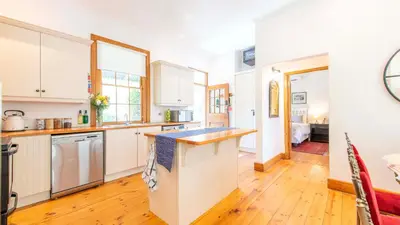 a kitchen with white cabinets and a wooden floor at Waymaker Cottage in Franschhoek