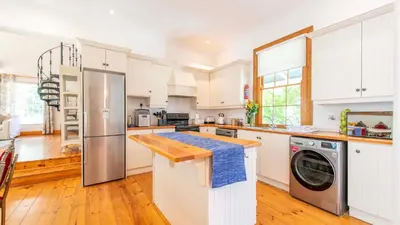 a kitchen with white cabinets and a washer and dryer at Waymaker Cottage in Franschhoek