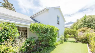 a white house with a garden in front of it at Waymaker Cottage in Franschhoek