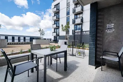 a patio with a table and chairs and a building at 318 Riverlands - Lux 1 bedroom Apartment in Cape Town