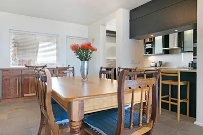 a kitchen with a wooden table with a vase of flowers at Dolphin Beach C111 Sea -Table Mountain Views at Dolphin Beach in Cape Town