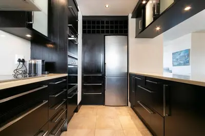 a kitchen with black cabinets and a refrigerator at Dolphin Beach C111 Sea -Table Mountain Views at Dolphin Beach in Cape Town