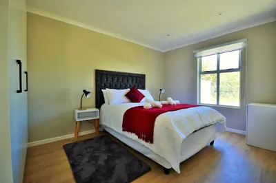 a bedroom with a bed with a red blanket and a window at Tweespruit Estate - Stellenbosch- 3 Bedroom House in Stellenbosch