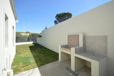 a bench sits on the side of a white wall at Tweespruit Estate - Stellenbosch- 3 Bedroom House in Stellenbosch