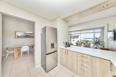 a kitchen and dining room with a table and a refrigerator at Beautiful & Modern Dolphin Beach CG12 by HMH in Cape Town