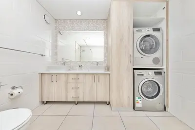 a bathroom with a washing machine and a sink at Beautiful & Modern Dolphin Beach CG12 by HMH in Cape Town