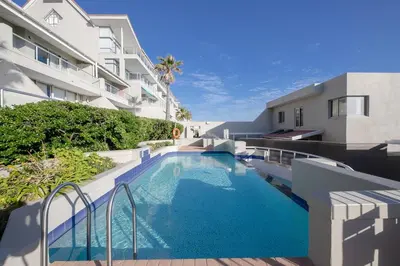 a swimming pool in front of a building at Beautiful & Modern Dolphin Beach CG12 by HMH in Cape Town