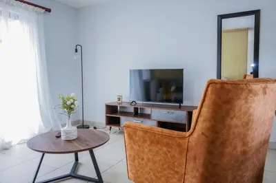a living room with a chair and a television at Modern 1BR Flat - Near Canal Walk in Cape Town