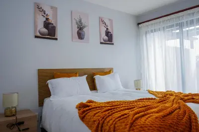 a bedroom with a bed with an orange blanket on it at Modern 1BR Flat - Near Canal Walk in Cape Town
