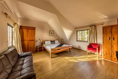 a bedroom with a bed and a couch in a room at Winelands Villa Guesthouse and Cottages in Somerset West