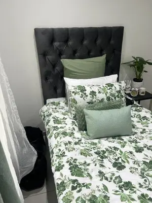 a bed with green and white sheets and pillows at Sunbird Poolhouse in Silver Sands