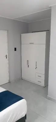 a white bedroom with white cabinets and a bed at RoomIsGood in Cape Town