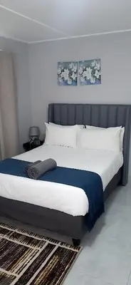 a bedroom with a large bed with a blue blanket at RoomIsGood in Cape Town