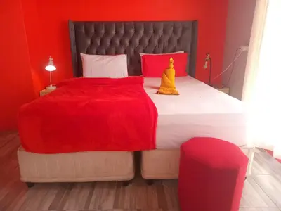 a bedroom with a large bed with a red wall at Neo & Ruks Rooms Parow 5 in Goodwood