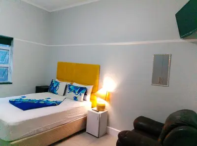 a small bedroom with a bed and a chair at Neo & Ruks Rooms Parow 5 in Goodwood