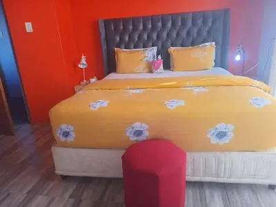 a bedroom with a large yellow bed with a red chair at Neo & Ruks Rooms Parow 5 in Goodwood