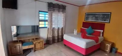 a bedroom with a bed and a flat screen tv at Neo & Ruks Rooms Parow 5 in Goodwood