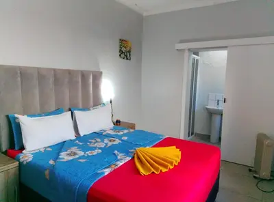 a bedroom with a bed with a red and blue blanket at Neo & Ruks Rooms Parow 5 in Goodwood