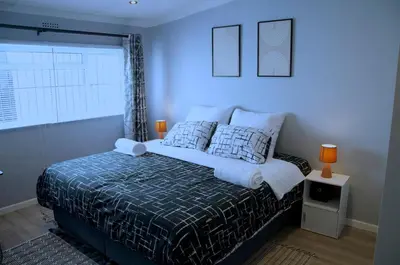a bedroom with a bed with a blue wall at Modern Stylish Home In Cape Town in Cape Town