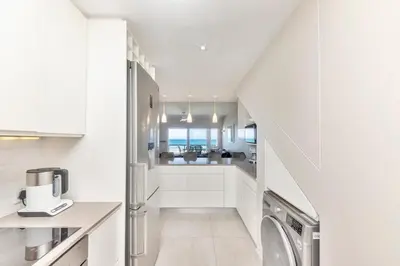 a white kitchen with a washer and dryer at Dolphin Beach H205 Beachfront APT, Blouberg by HMH in Cape Town