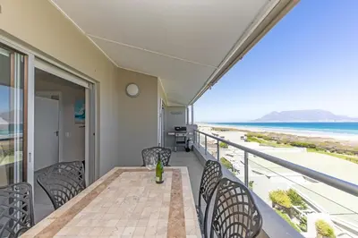a balcony with a table and chairs and the ocean at Dolphin Beach H205 Beachfront APT, Blouberg by HMH in Cape Town