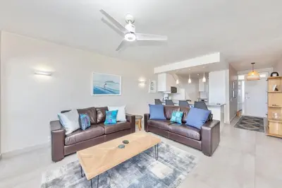 a living room with two couches and a coffee table at Dolphin Beach H205 Beachfront APT, Blouberg by HMH in Cape Town