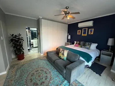 a bedroom with a bed and a couch and a ceiling fan at Queens Corner in Wellington