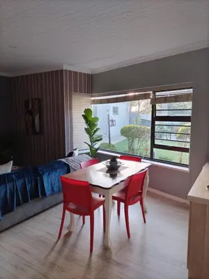 a living room with a table and chairs and a bed at Queens Corner in Wellington