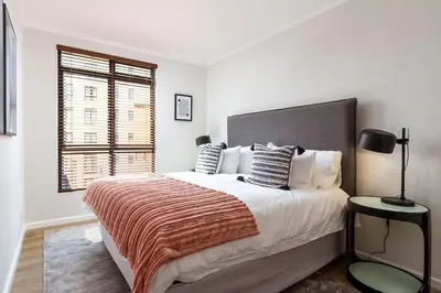 a white bedroom with a large bed and a window at Luxurious Palm View Apartment Cape Town in Cape Town
