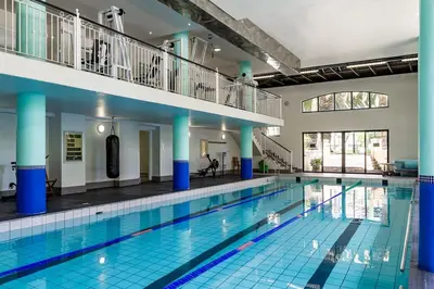 a large swimming pool with blue tiles in a building at Luxurious Palm View Apartment Cape Town in Cape Town