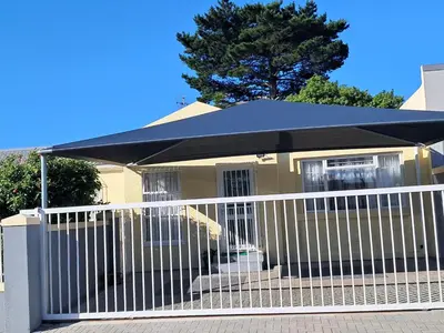 a white fence with an umbrella in front of a house at Deo Volente Self-Catering Cottage in Kuilsrivier