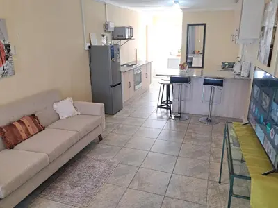 a living room with a couch and a kitchen at Deo Volente Self-Catering Cottage in Kuilsrivier