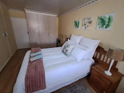 a bedroom with a bed with white sheets and pillows at Deo Volente Self-Catering Cottage in Kuilsrivier