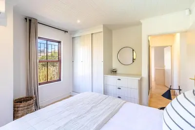 a white bedroom with a large bed and a window at Franschhoek Charm in Franschhoek