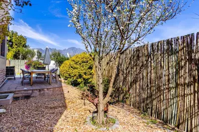 a table and a tree in front of a fence at Franschhoek Charm in Franschhoek