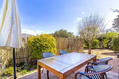 a wooden table with chairs and an umbrella at Franschhoek Charm in Franschhoek