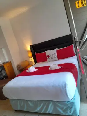 a bedroom with a large bed with red and white pillows at Goodwood Neo & Ruks guest house in Goodwood