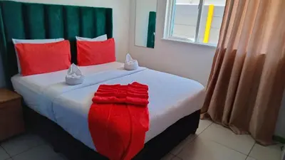 a bed with red pillows and a red blanket on it at Goodwood Neo & Ruks guest house in Goodwood