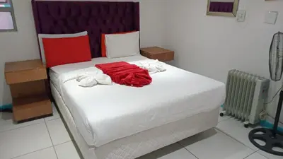 a bedroom with a white bed with a red shirt on it at Goodwood Neo & Ruks guest house in Goodwood