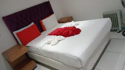 a large white bed with a red dress on it at Goodwood Neo & Ruks guest house in Goodwood