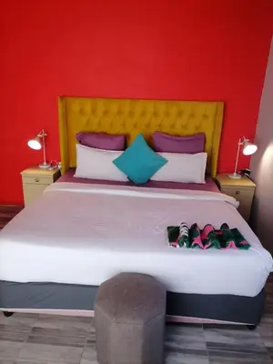 a bedroom with a large bed with a red wall at Parow Neo & Ruks Rooms 9 in Avondale