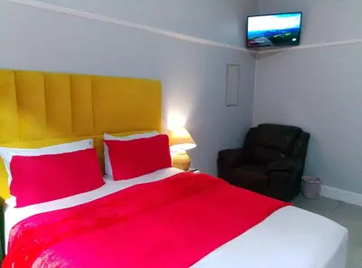 a bedroom with a bed with red pillows and a chair at Parow Neo & Ruks Rooms 9 in Avondale