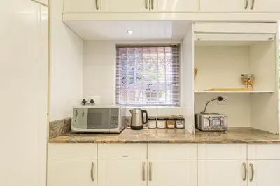 a kitchen with white cabinets and a microwave on a counter at TwinPalace in Plattekloof