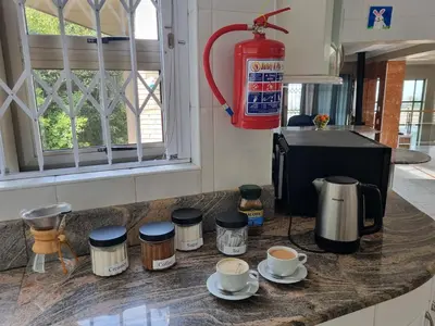 a kitchen counter with cups of coffee and a fire extinguisher at TwinPalace in Plattekloof