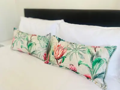 a bed with two pillows with palm trees on it at Bahlaloga Studio Durbanville in Durbanville