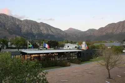 a building with flags in front of a mountain at Tram View Hideaway in Franschhoek