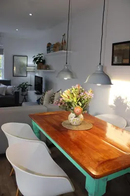 a living room with a wooden table and white chairs at Tram View Hideaway in Franschhoek